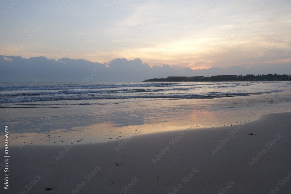 Empty beach at early morning, pink sunrise reflected in water