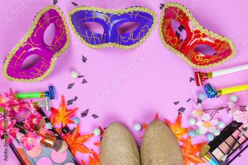 Flat lay top veiw of mask party preparation accessories. cosmetics and brushes on pink background