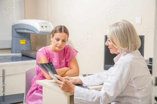 Foto Female doctor analyzing x-ray scan of female patient