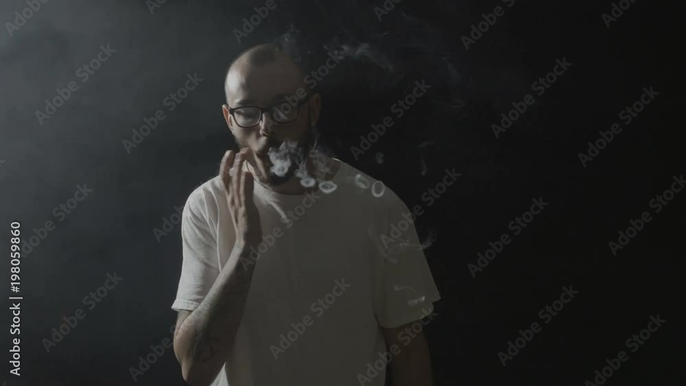 custom made wallpaper toronto digitalYoung man wearing glasses inhaling smoke and practicing various vaping tricks making circles in a dark room