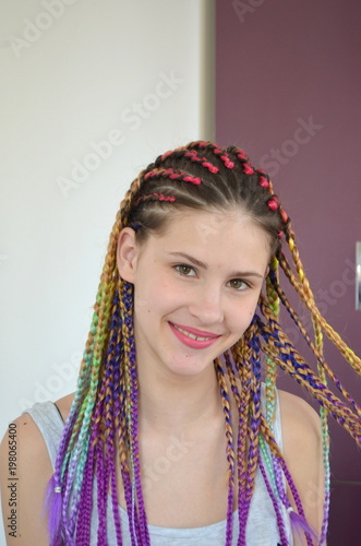 Девушка с модным набором разноцветных косичек Канекалон. Цветные искусственные пряди волос. Материал для плетения.
