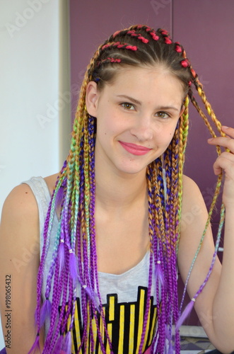 Девушка с модным набором разноцветных косичек Канекалон. Цветные искусственные пряди волос. Материал для плетения.