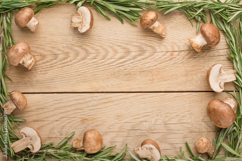 Champignons with rosemary on a wooden texture. Top view, with an empty space for inscription or advertising.