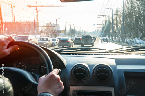 Hands on the steering wheel. View of the road in the city through the windshield of the car photo