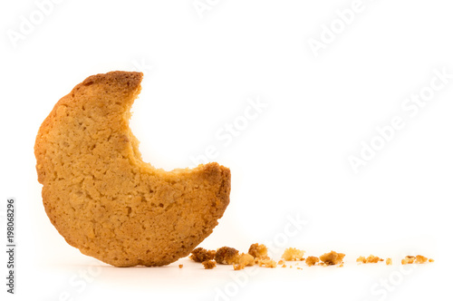 Peanut butter cookie on a white background. Golden homemade biscuit with a missing bite and trail of crumbs. A tempting snack.