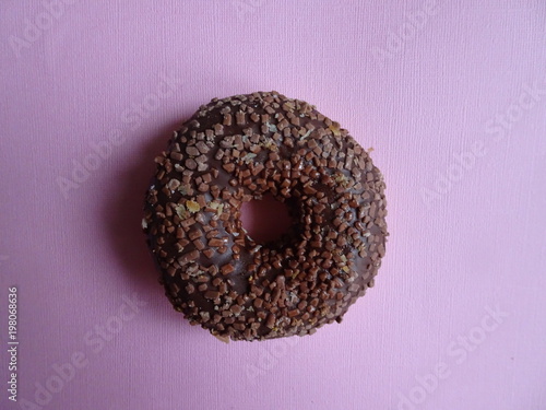 Yummy chocolate donut on violet background. Top view