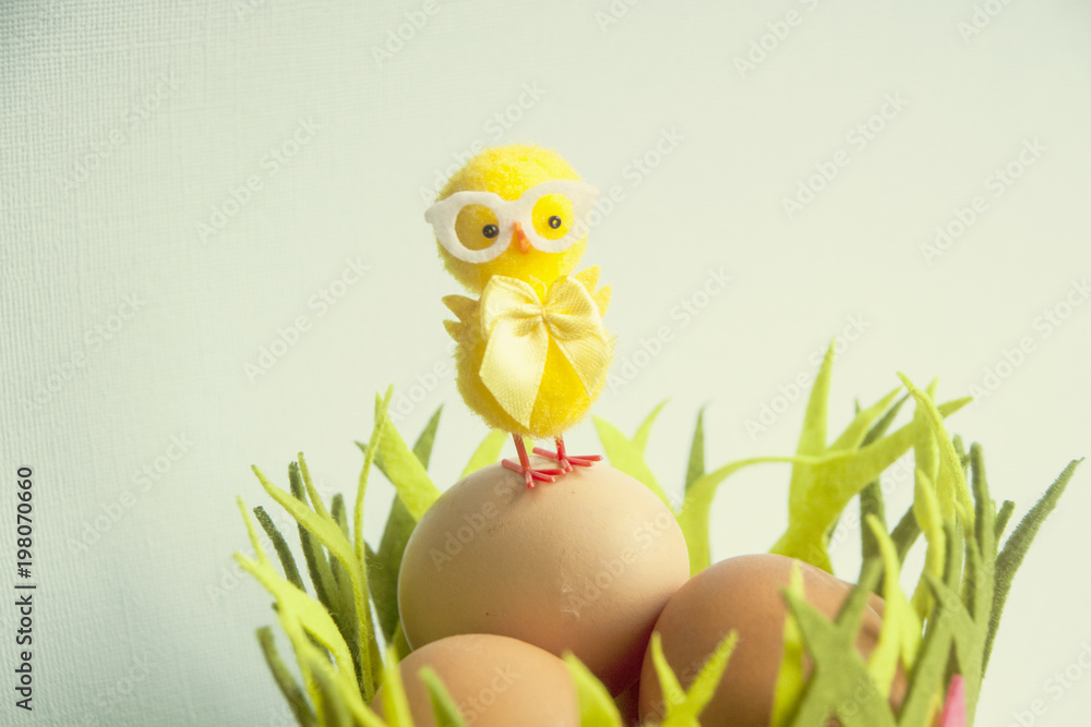 Fototapeta premium Cute Yellow chicken standing on Easter eggs among grass