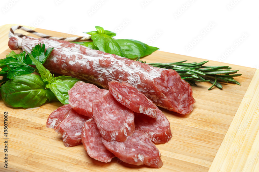 Dried sliced organic salami sausage on wooden cutting board