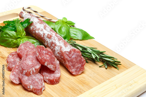 Dried sliced organic salami sausage on wooden cutting board