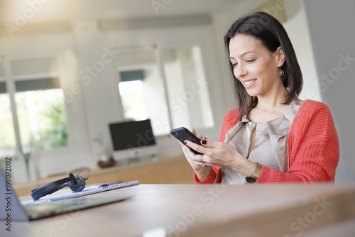 Brunette woman using smartphone in office