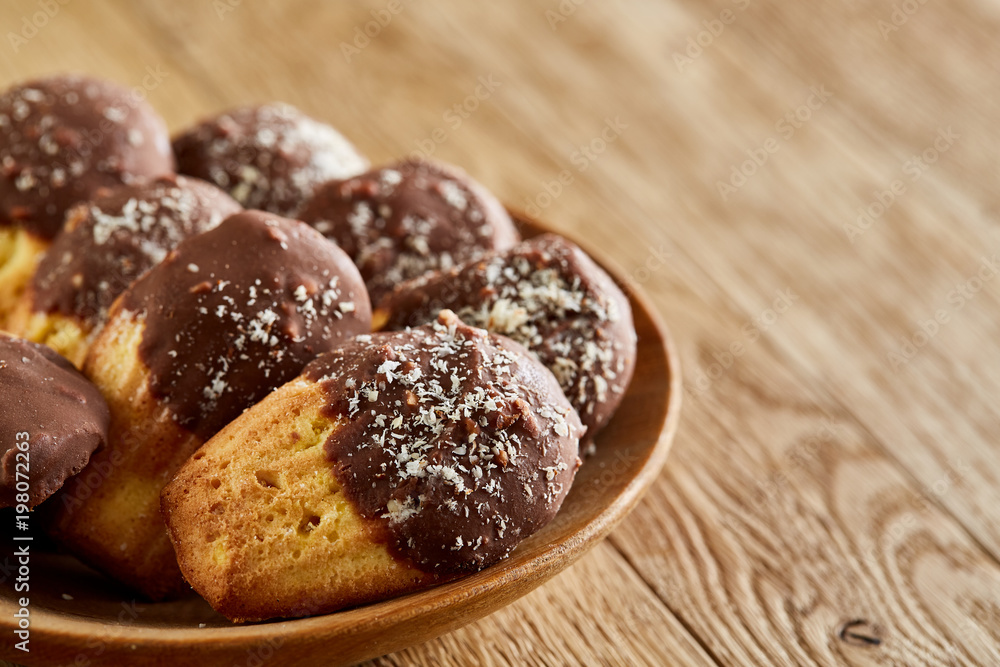 Freshly baked almond cookies piled on ceramic plate over rustic background, top view, close-up, selective focus