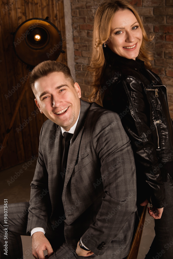 Obraz premium Portrait of beautiful young couple in suit and leather jacket hugging and smiling.