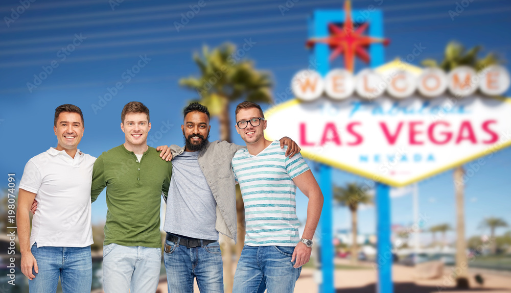 diversity, tourism and travel concept - international group of happy smiling men or friends over welcome to fabulous las vegas sign background