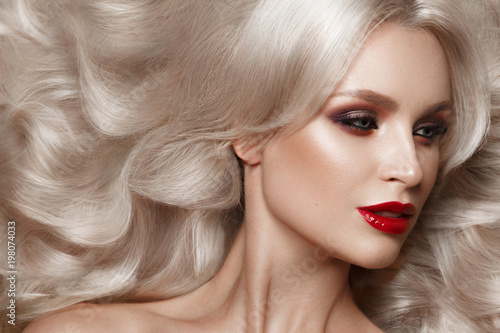 Beautiful blonde in a Hollywood manner with curls, natural makeup and red lips.. Beauty face and hair. Picture taken in the studio