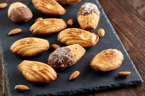 Freshly baked almond cookies on stone board over wooden background, top view, selective focus.