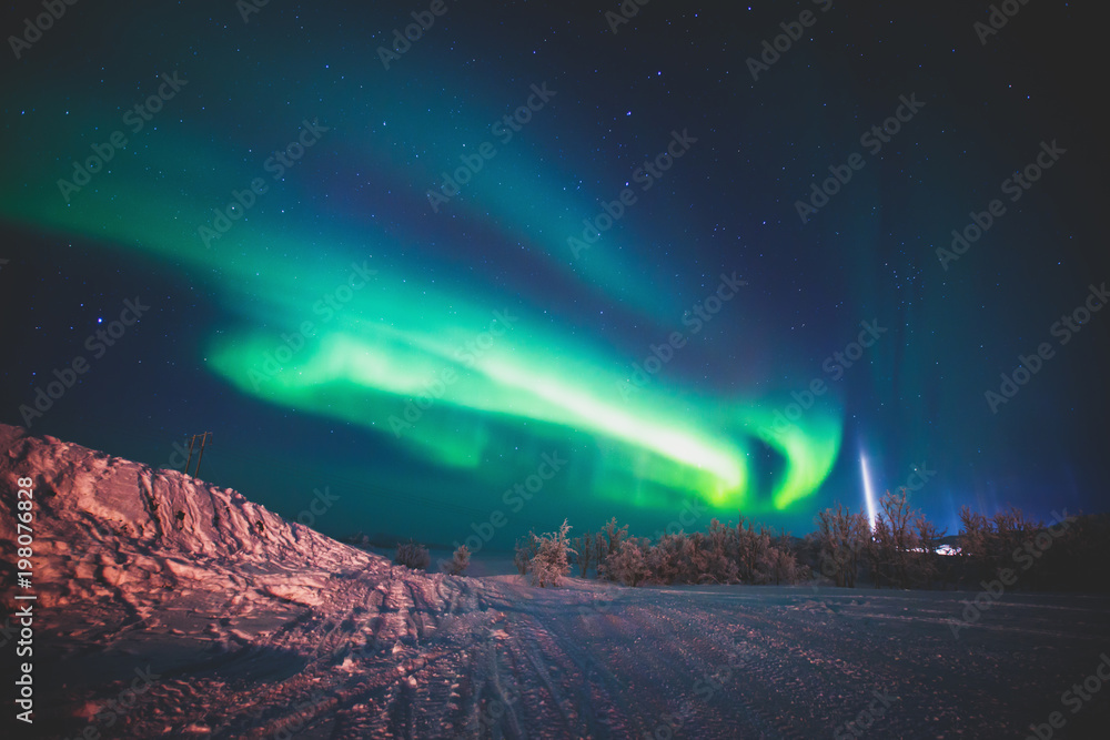 Beautiful picture of massive multicolored green vibrant Aurora Borealis, also known as Northern Lights in the night sky over winter Lapland landscape, Norway, Scandinavia