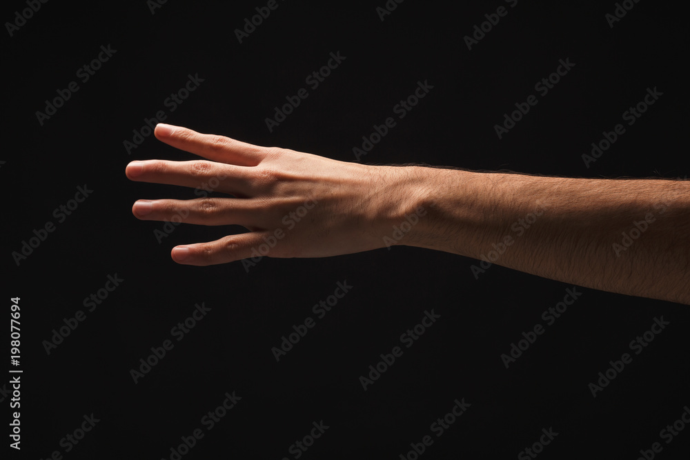 Male hand shows number four isolated at black