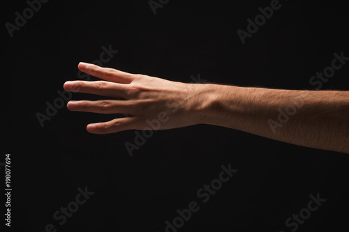 Male hand shows number four isolated at black