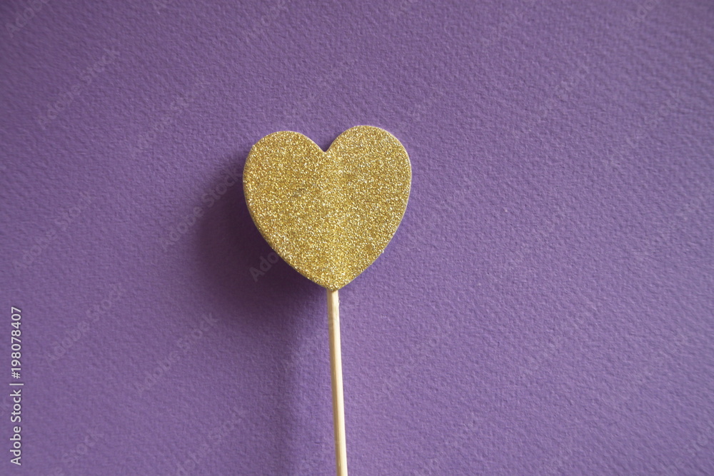 Gold glittering heart on violet background. Shimmering party stick Gold glittering heart on violet background. Shimmering party stick