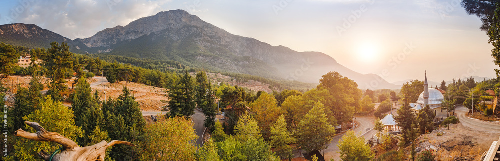 Scenic panorama of village in mountains with lone mosque at the sunset, travel in Turkey