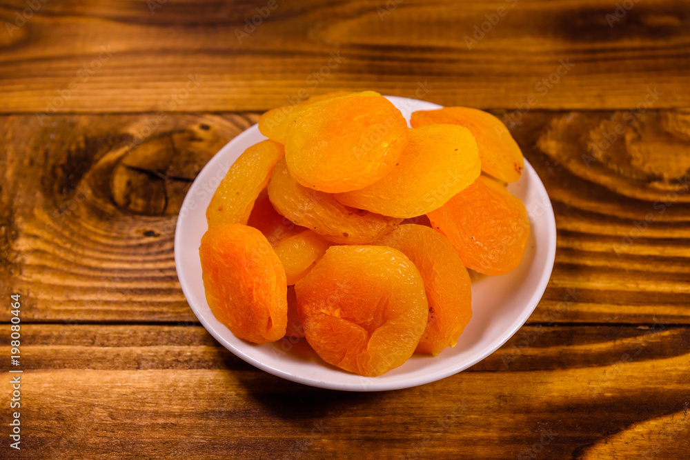 Ceramic plate with dried apricots on wooden table Ceramic plate with dried apricots on wooden table