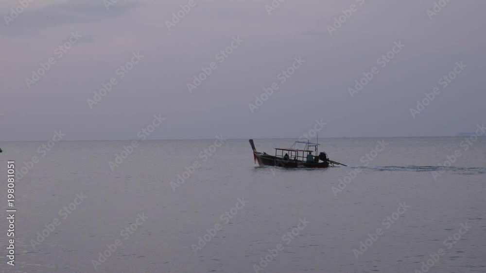 Thai Wooden Fisherman long tail Boat Sail in the Tropical Sunset sea. Thai Wooden Fisherman long tail Boat Sail in the Tropical Sunset sea.