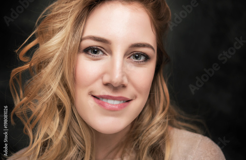 Portrait of an attractive young blonde woman on a black background.