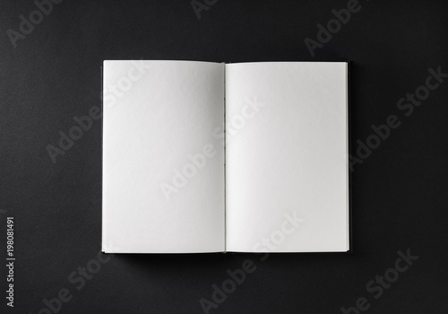 Blank open book, brochure or magazine on black paper background. Responsive design mockup. Flat lay.