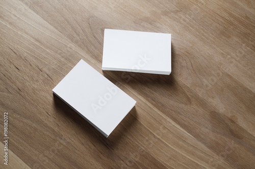 Blank white business cards on wooden table background. Mockup for branding identity. Studio shot.