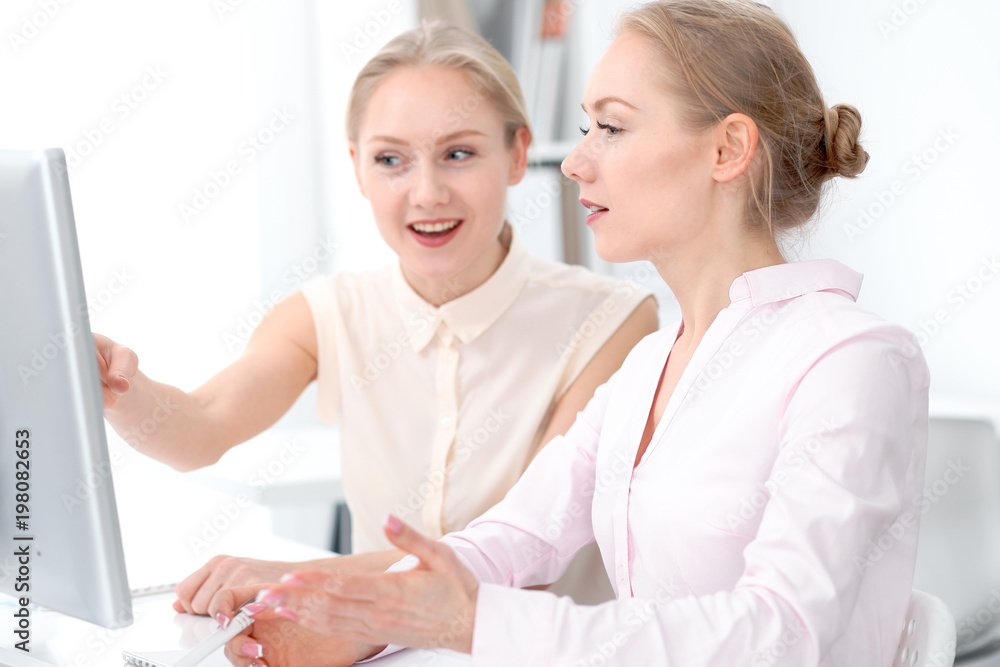 Two business ladies or colleagues discussing something in office background Two business ladies or colleagues discussing something in office background