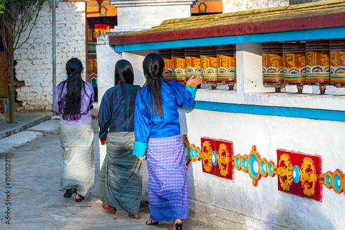 Fotografie Local Bhutanese women turning prayer wheels in a Buddhist temple near Trashigang