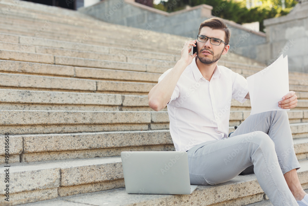 Thoughtful young businessman multitasking outdoors Thoughtful young businessman multitasking outdoors