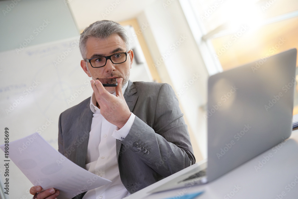 Naklejka premium Businessman in office using smartphone