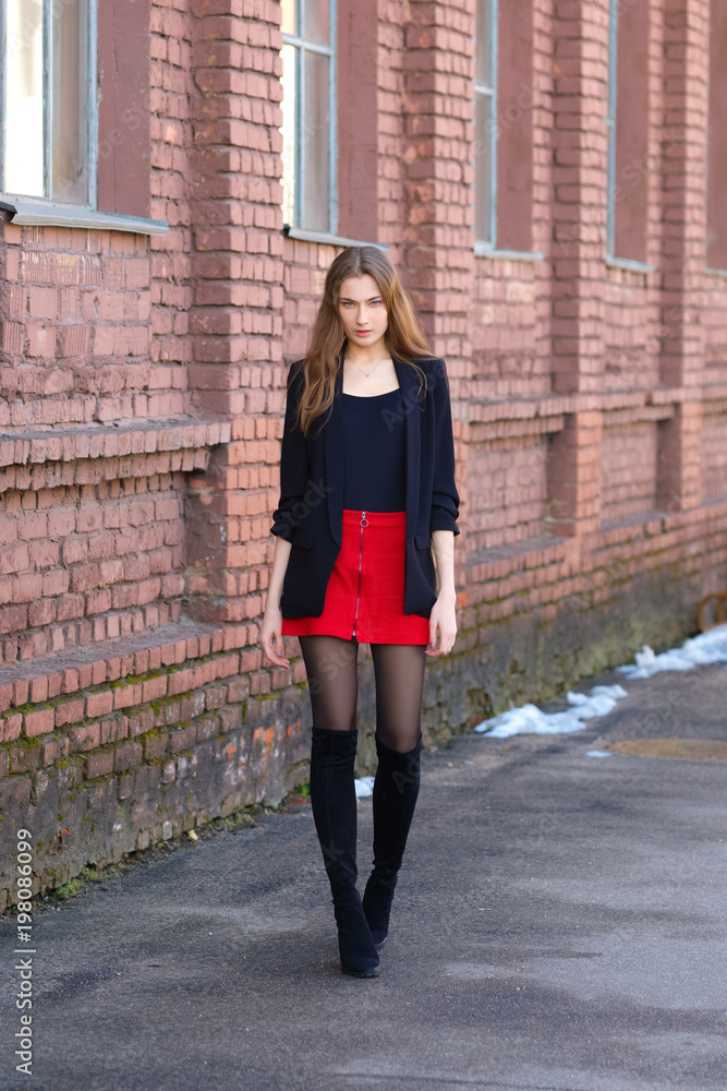Street fashion, urban style. Girl in jacket, t-shirt, short skirt and high boots