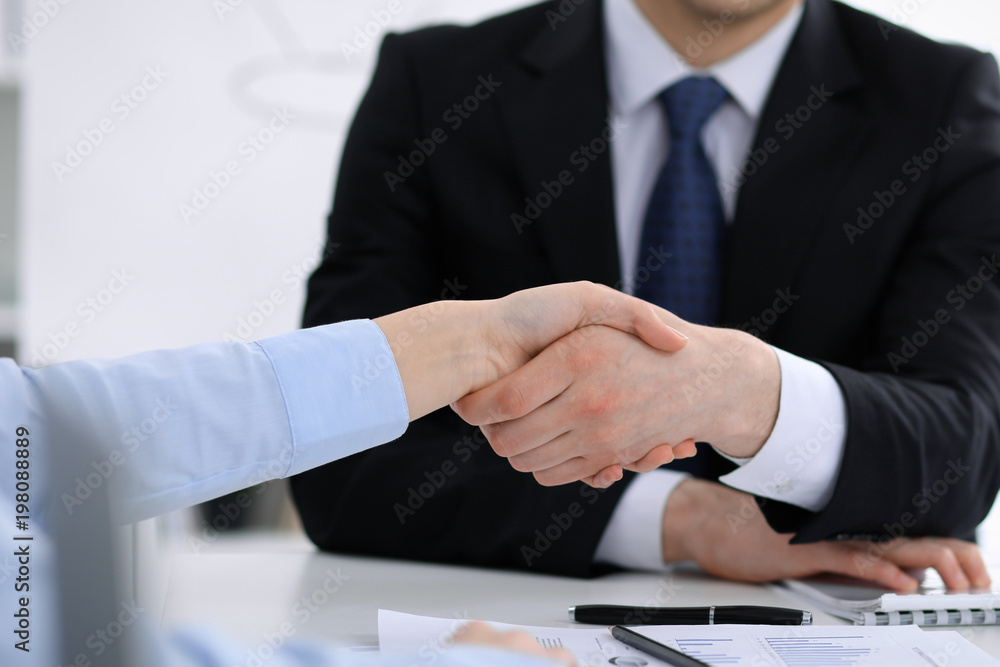 Close Up of unknown business people shaking hands while finishing up a meeting. Handshaking, agreement or success concept in people communication Close Up of unknown business people shaking hands while finishing up a meeting. Handshaking, agreement or success concept in people communication