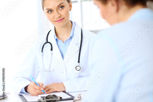 Friendly smiling doctor  and  patient sitting at the table