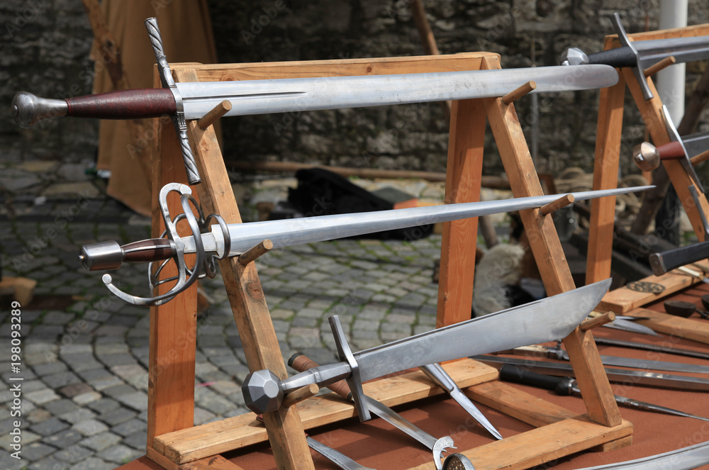 Different medieval styled swords on wooden racks
