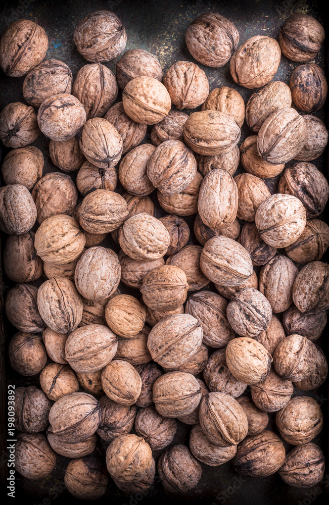 Walnuts overhead closeup large arrangement in peel on dark background in studio Walnuts overhead closeup large arrangement in peel on dark background in studio