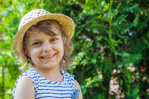 A smiling or laughing little girl in a straw hat, summertime vacation