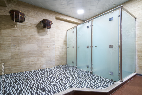 Fotografía Three empty public showers with wooden ice bucket for health, sauna showers inte