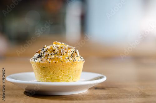Corn muffin with poppy, sesame and sunflower seeds on a plate with blurred background