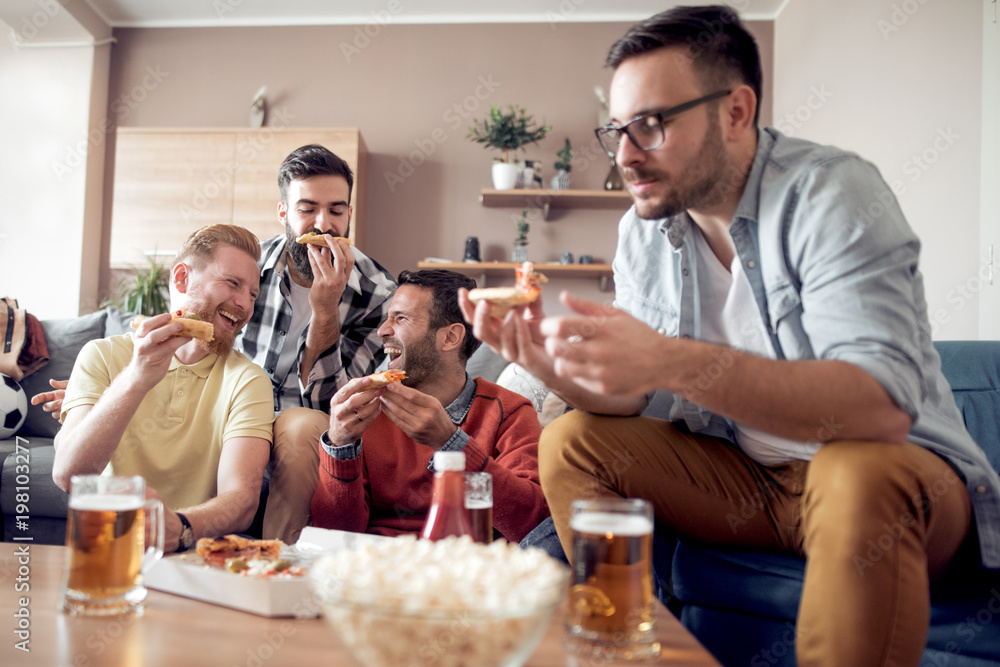 Male friends having pizza party at home