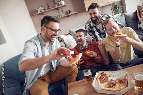 Male friends having pizza party at home photo
