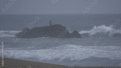 Fisherman Standing Between Lots Of Wavebreakers  (180fps Slow Motion) photo