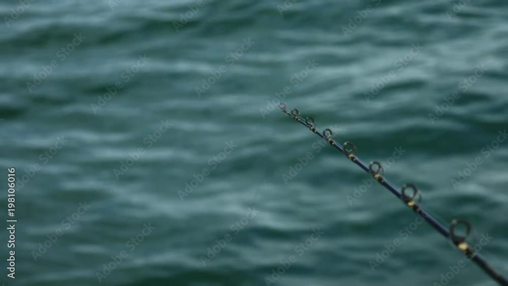 Close up holding fishing rod over blue sea Close up holding fishing rod over blue sea