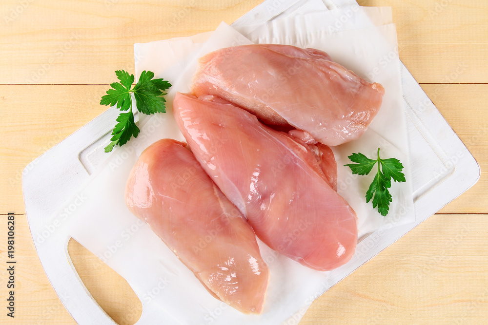 raw chicken fillets on wooden cutting board. raw chicken fillets on wooden cutting board.