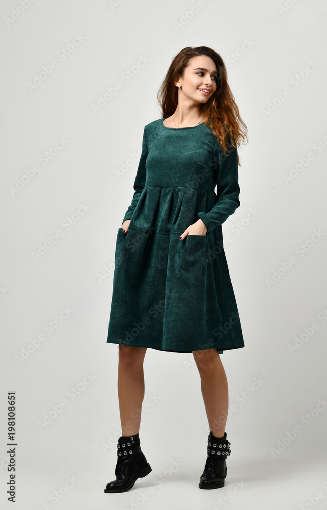 Young beautiful woman posing in new casual winter green dress on a grey Young beautiful woman posing in new casual winter green dress on a grey