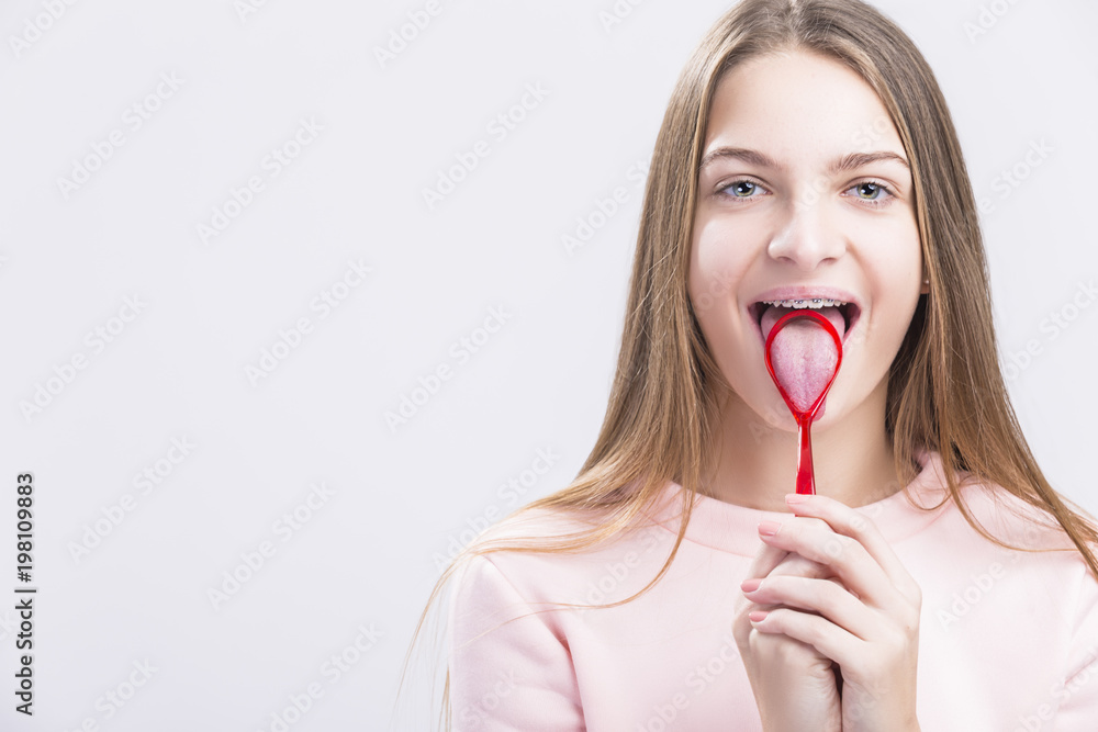 Dental Health Concepts. Closeup Portrait of Caucasian Teenage Girl with Correcting Teeth Brackets. Posing with Special Tongue Cleaning Brush. Dental Health Concepts. Closeup Portrait of Caucasian Teenage Girl with Correcting Teeth Brackets. Posing with Special Tongue Cleaning Brush.