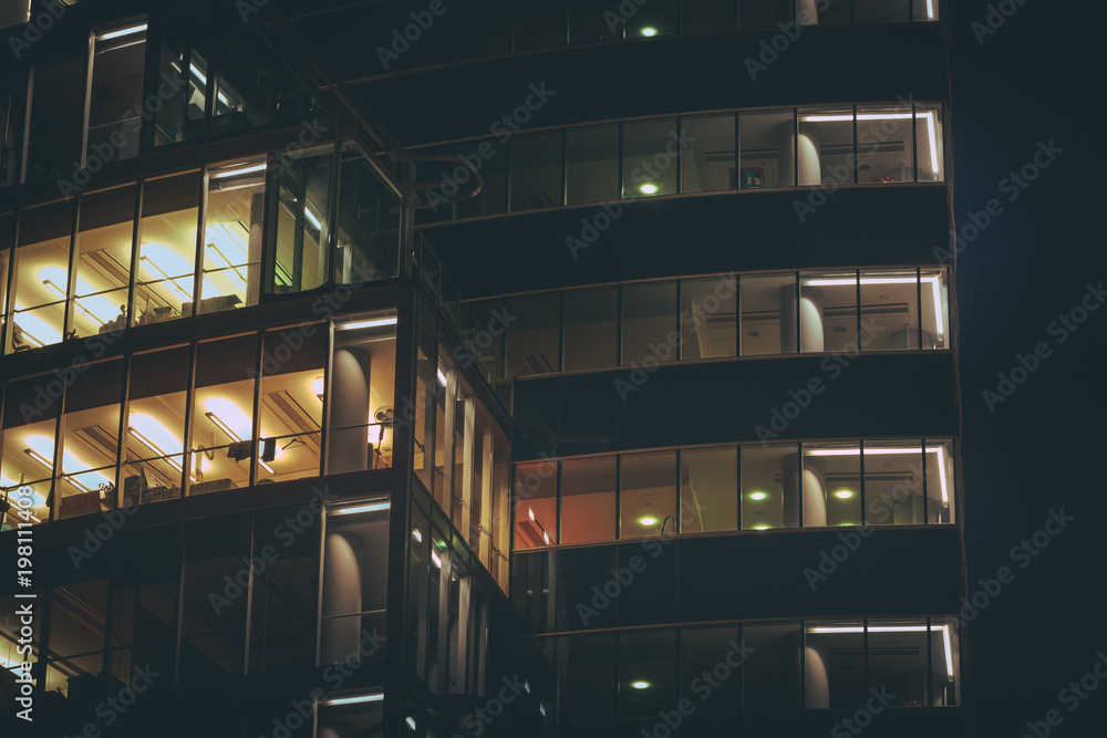 Modern office building made from glass at night time. Lights in the office windows. Modern architecture skyscraper.
