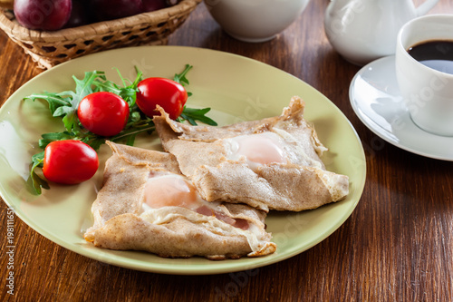 Crepes with ham, cheese and poached egg on a plate
